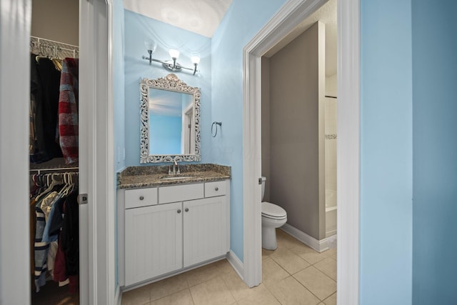 bathroom featuring tile patterned floors, vanity, toilet, and a spacious closet