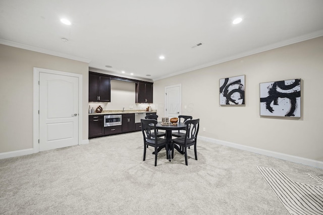 dining area featuring indoor wet bar, recessed lighting, ornamental molding, and light carpet