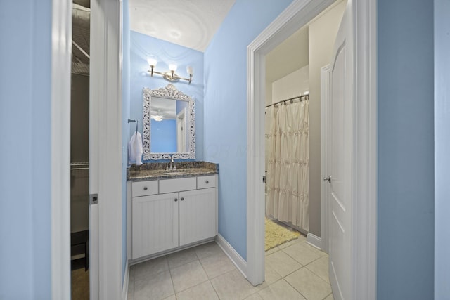 bathroom featuring a shower with curtain, baseboards, tile patterned flooring, and vanity