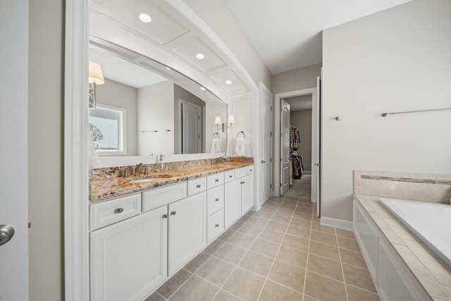 full bath featuring a walk in closet, a sink, double vanity, tile patterned floors, and baseboards