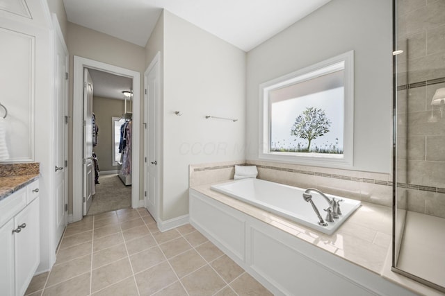 full bath with tile patterned flooring, baseboards, a garden tub, and vanity