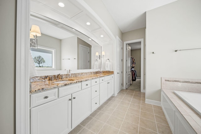 bathroom featuring double vanity, a washtub, baseboards, a spacious closet, and a sink