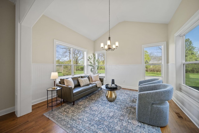 living room featuring a chandelier, visible vents, wood finished floors, a wainscoted wall, and lofted ceiling