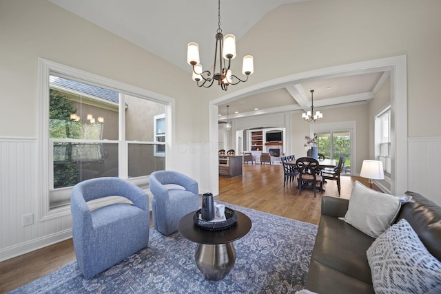 living room with an inviting chandelier, wainscoting, a decorative wall, wood finished floors, and arched walkways