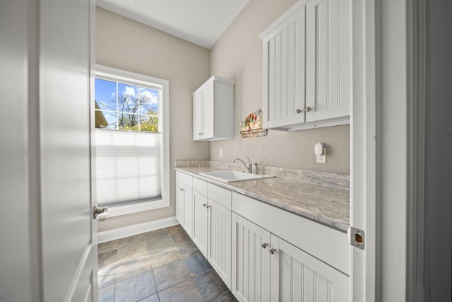 interior space with baseboards, a sink, and stone finish flooring