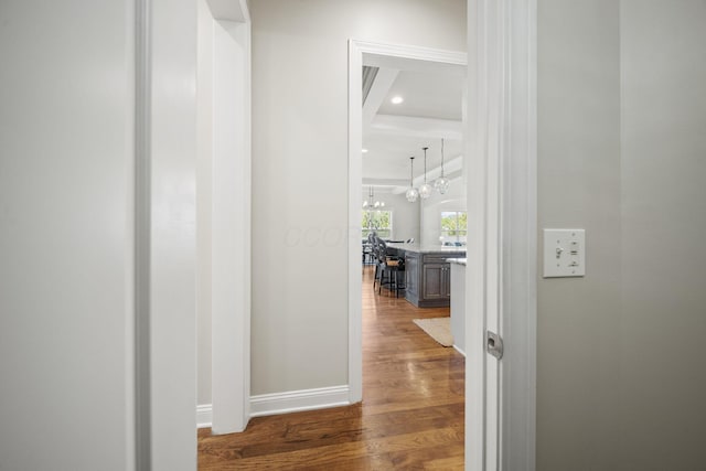 corridor featuring baseboards, recessed lighting, wood finished floors, and a notable chandelier