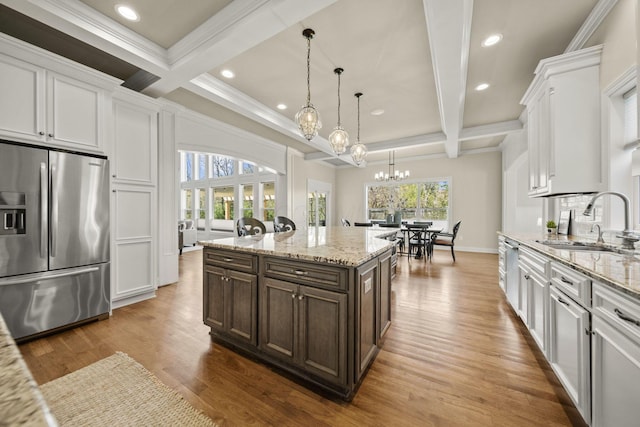 kitchen featuring wood finished floors, dark brown cabinetry, white cabinetry, a sink, and appliances with stainless steel finishes
