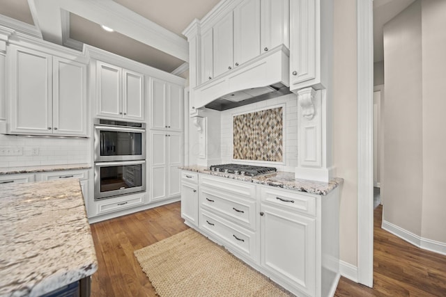 kitchen with white cabinets, stainless steel appliances, decorative backsplash, and wood finished floors