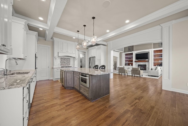 kitchen featuring appliances with stainless steel finishes, a fireplace, a sink, open floor plan, and recessed lighting