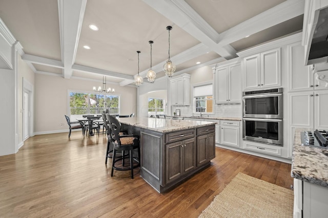 kitchen featuring white cabinets, double oven, an inviting chandelier, coffered ceiling, and recessed lighting