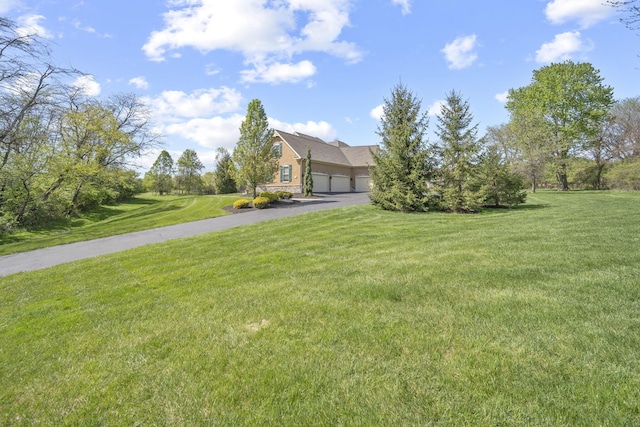 view of front of house with an attached garage, a front lawn, and driveway