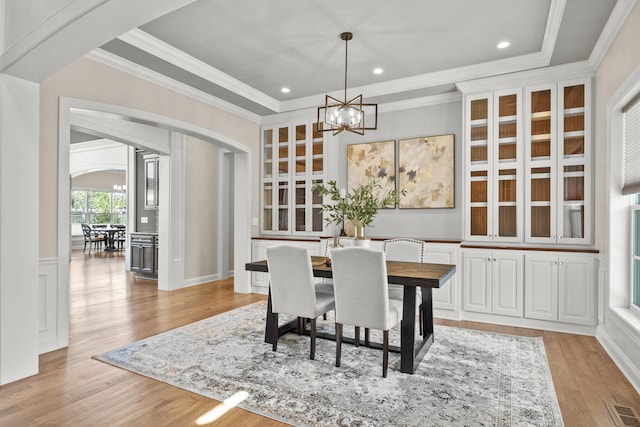 dining area with visible vents, crown molding, arched walkways, a chandelier, and light wood-style flooring