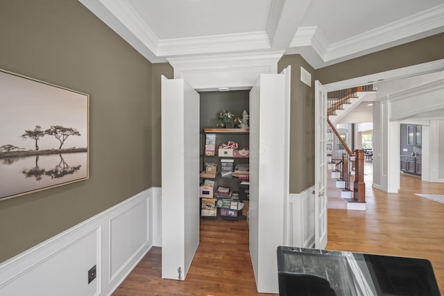 corridor with ornamental molding, stairway, and a decorative wall