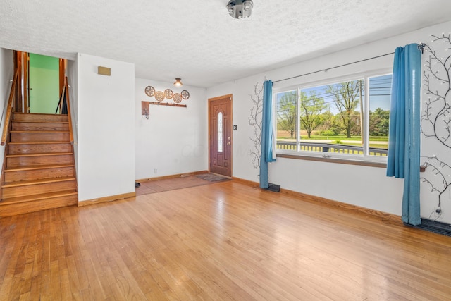 14 Stoney Ridge Dr SW, Pataskala, OH 43062 - unfurnished living room featuring a textured ceiling, baseboards, stairway, and hardwood / wood-style floors