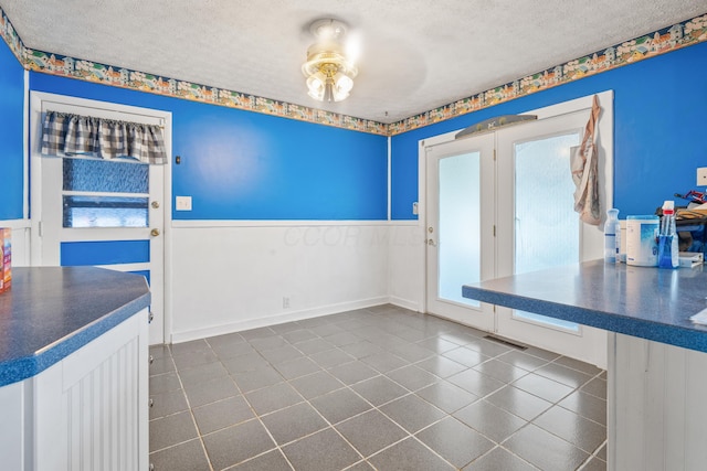 14 Stoney Ridge Dr SW, Pataskala, OH 43062 - unfurnished dining area featuring dark tile patterned floors, a textured ceiling, and a wainscoted wall
