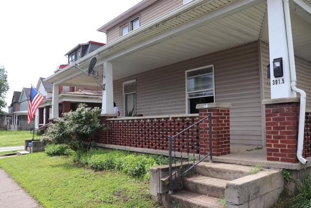 view of property exterior with a porch, a yard, and brick siding