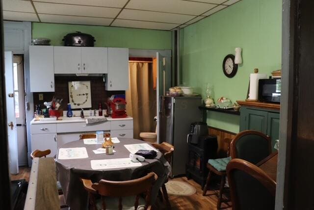 kitchen featuring black microwave, a drop ceiling, and white cabinetry