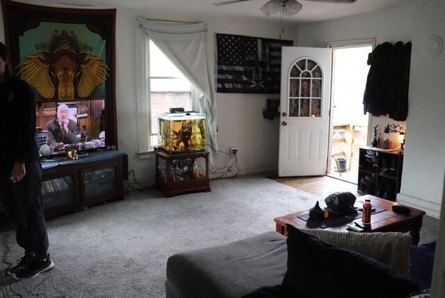 carpeted living area with a ceiling fan