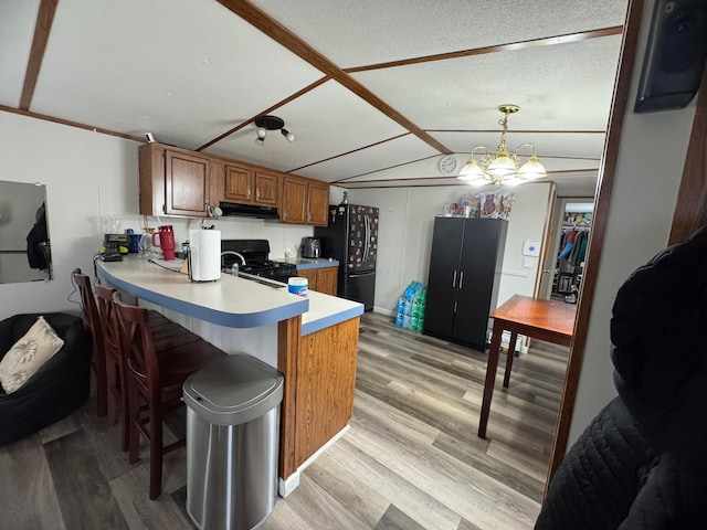1049 Harmon Ave Unit C82, Columbus, OH 43223 - kitchen with black appliances, brown cabinets, under cabinet range hood, and light wood-type flooring