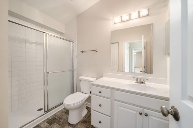 bathroom featuring toilet, a shower stall, and vanity