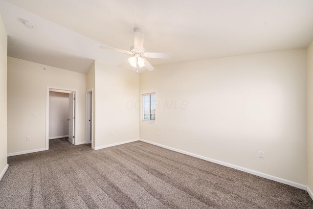 carpeted empty room featuring a ceiling fan and baseboards