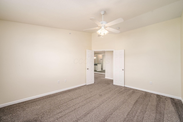 carpeted empty room with baseboards and a ceiling fan