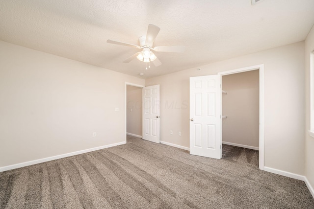 unfurnished bedroom featuring carpet floors, baseboards, ceiling fan, and a spacious closet