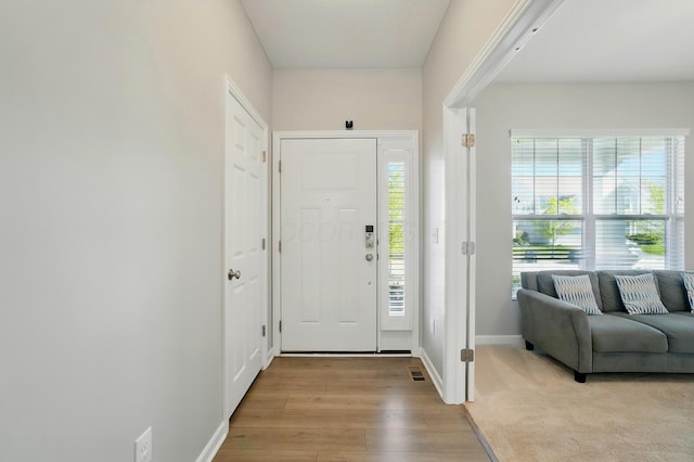 foyer entrance with baseboards, light wood-type flooring, and visible vents