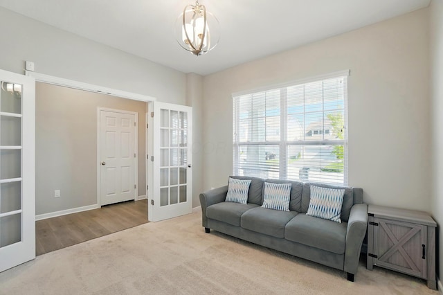 interior space with an inviting chandelier, baseboards, wood finished floors, and french doors