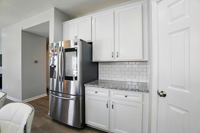 kitchen featuring light stone countertops, dark wood-style floors, stainless steel refrigerator with ice dispenser, white cabinets, and tasteful backsplash