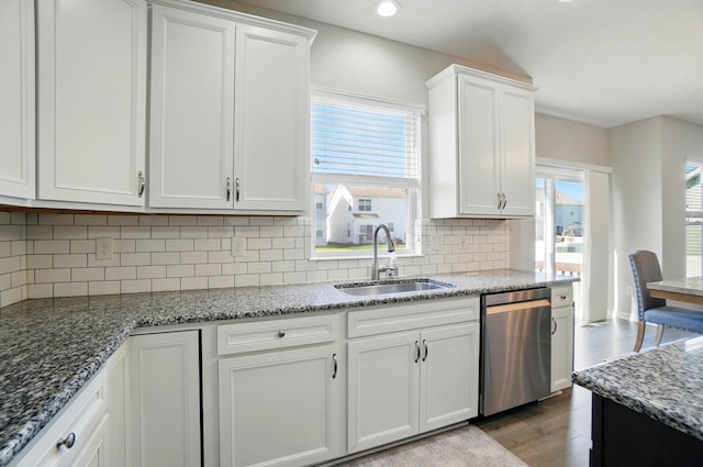 kitchen with backsplash, dishwasher, a sink, white cabinets, and light wood-style floors
