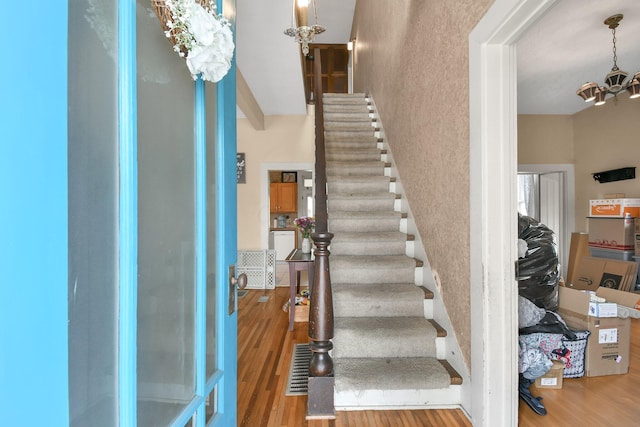 stairway with a chandelier and wood finished floors