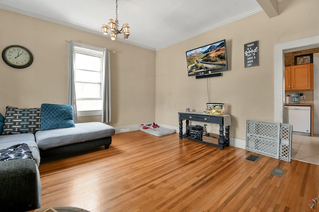 living area with visible vents, light wood-type flooring, ornamental molding, and a notable chandelier