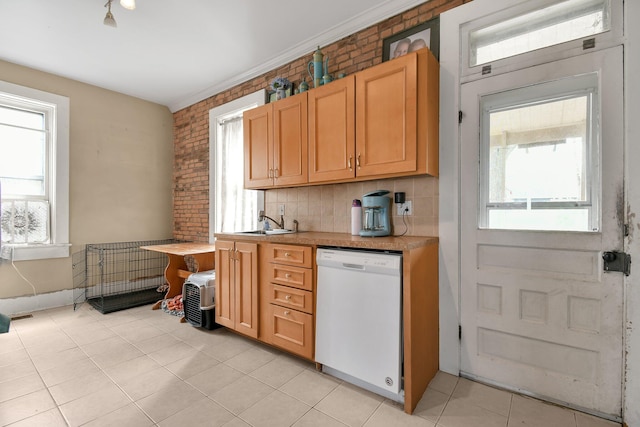 kitchen featuring tasteful backsplash, a sink, light countertops, white dishwasher, and light tile patterned flooring