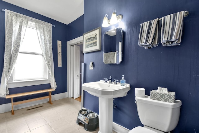 bathroom featuring tile patterned flooring, toilet, a sink, baseboards, and visible vents