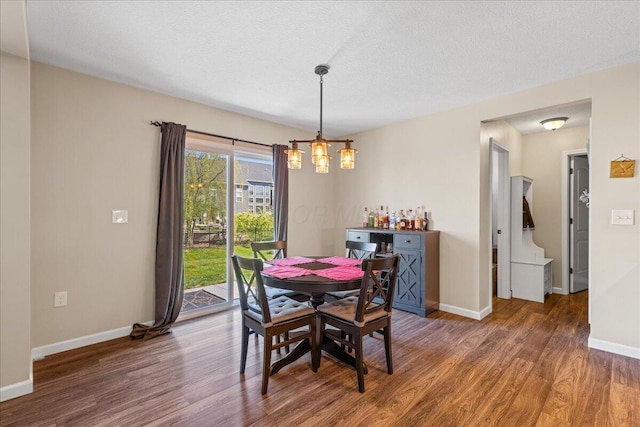 dining space featuring baseboards, a textured ceiling, and wood finished floors