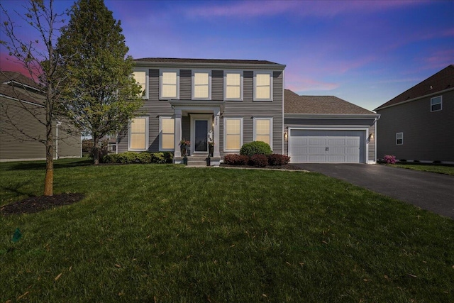colonial house featuring an attached garage, a lawn, and driveway