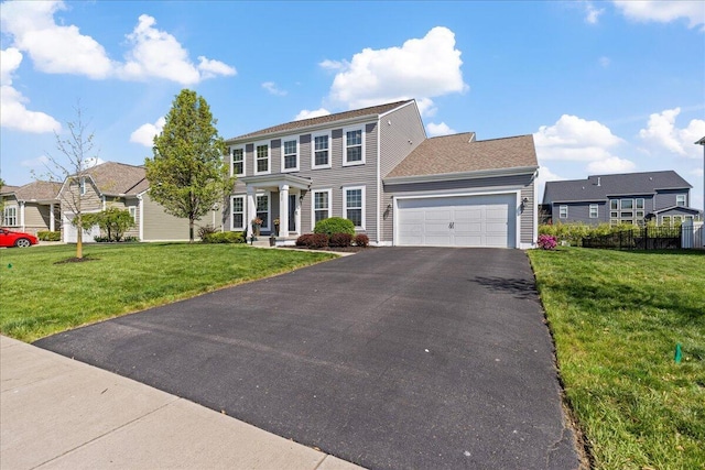 colonial-style house with an attached garage, a front lawn, and aphalt driveway