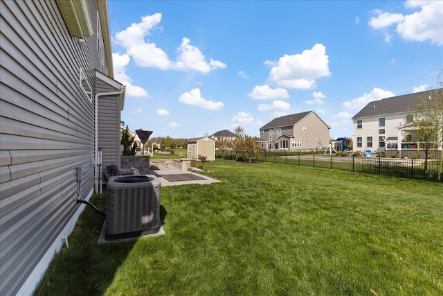 view of yard with fence, cooling unit, a shed, an outbuilding, and a residential view