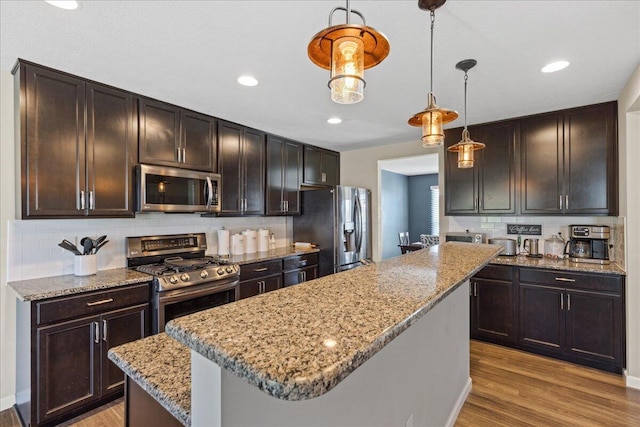 kitchen featuring a center island, light wood-type flooring, backsplash, and stainless steel appliances