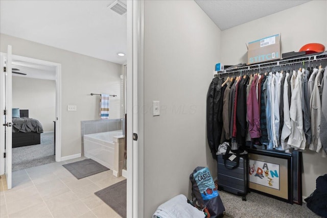 walk in closet with carpet flooring, tile patterned floors, and visible vents