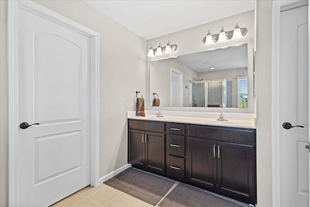 full bathroom with double vanity, tile patterned flooring, a stall shower, a sink, and baseboards