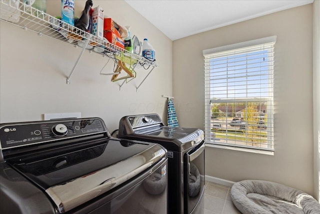 washroom featuring washing machine and clothes dryer, laundry area, baseboards, and a wealth of natural light