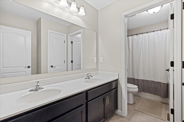 bathroom featuring double vanity, toilet, tile patterned floors, and a sink