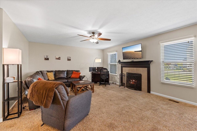 living area featuring ceiling fan, light colored carpet, baseboards, a tile fireplace, and visible vents