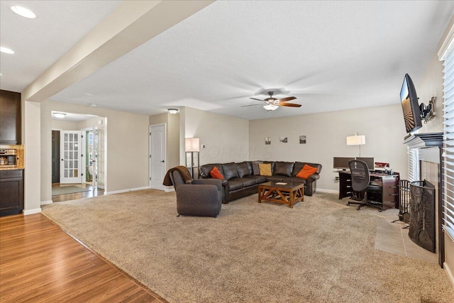 living area featuring a fireplace, baseboards, recessed lighting, a ceiling fan, and light wood-style flooring