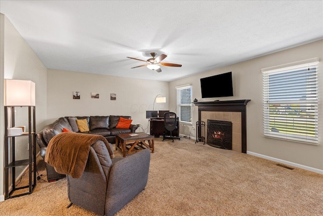 living room with ceiling fan, light carpet, baseboards, a tile fireplace, and visible vents