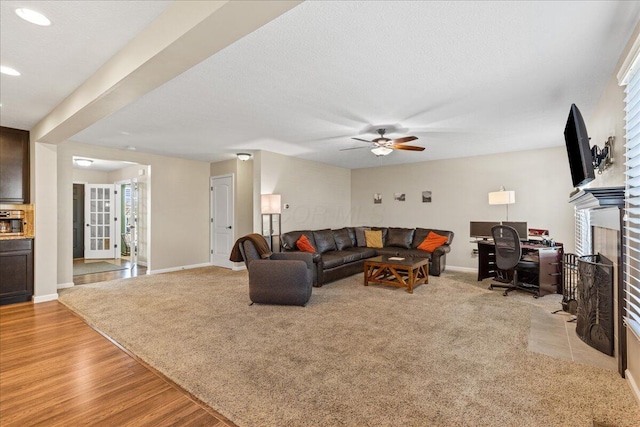 living room featuring a fireplace, baseboards, light wood-style floors, recessed lighting, and a ceiling fan