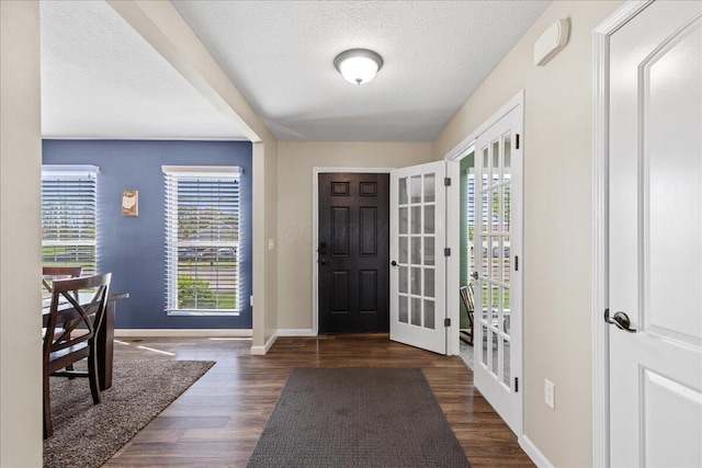 entrance foyer with baseboards, a textured ceiling, wood finished floors, and a healthy amount of sunlight