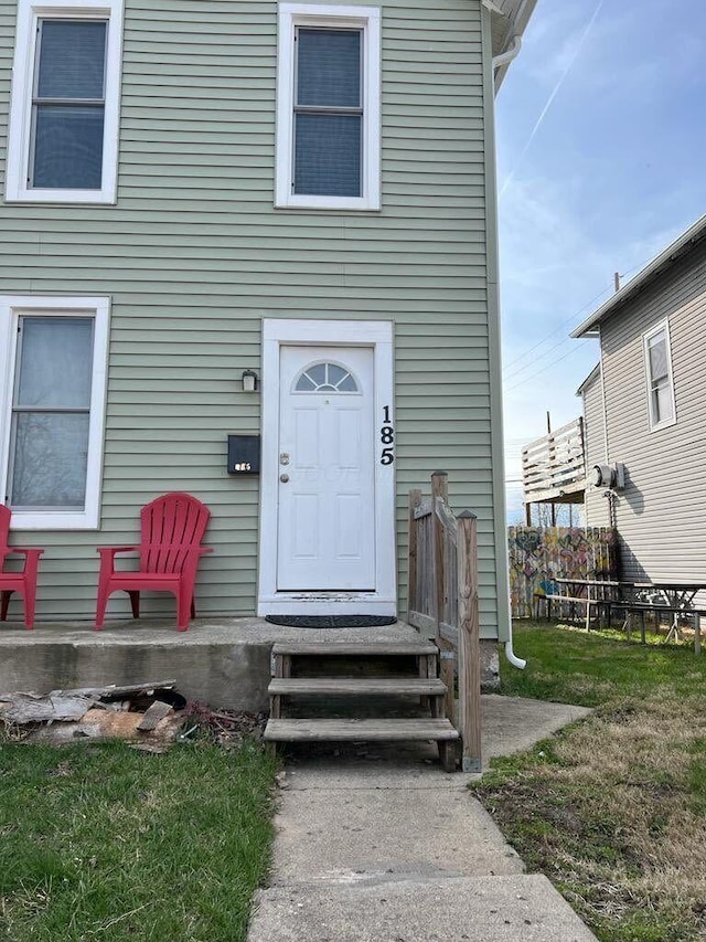 property entrance featuring a lawn and fence